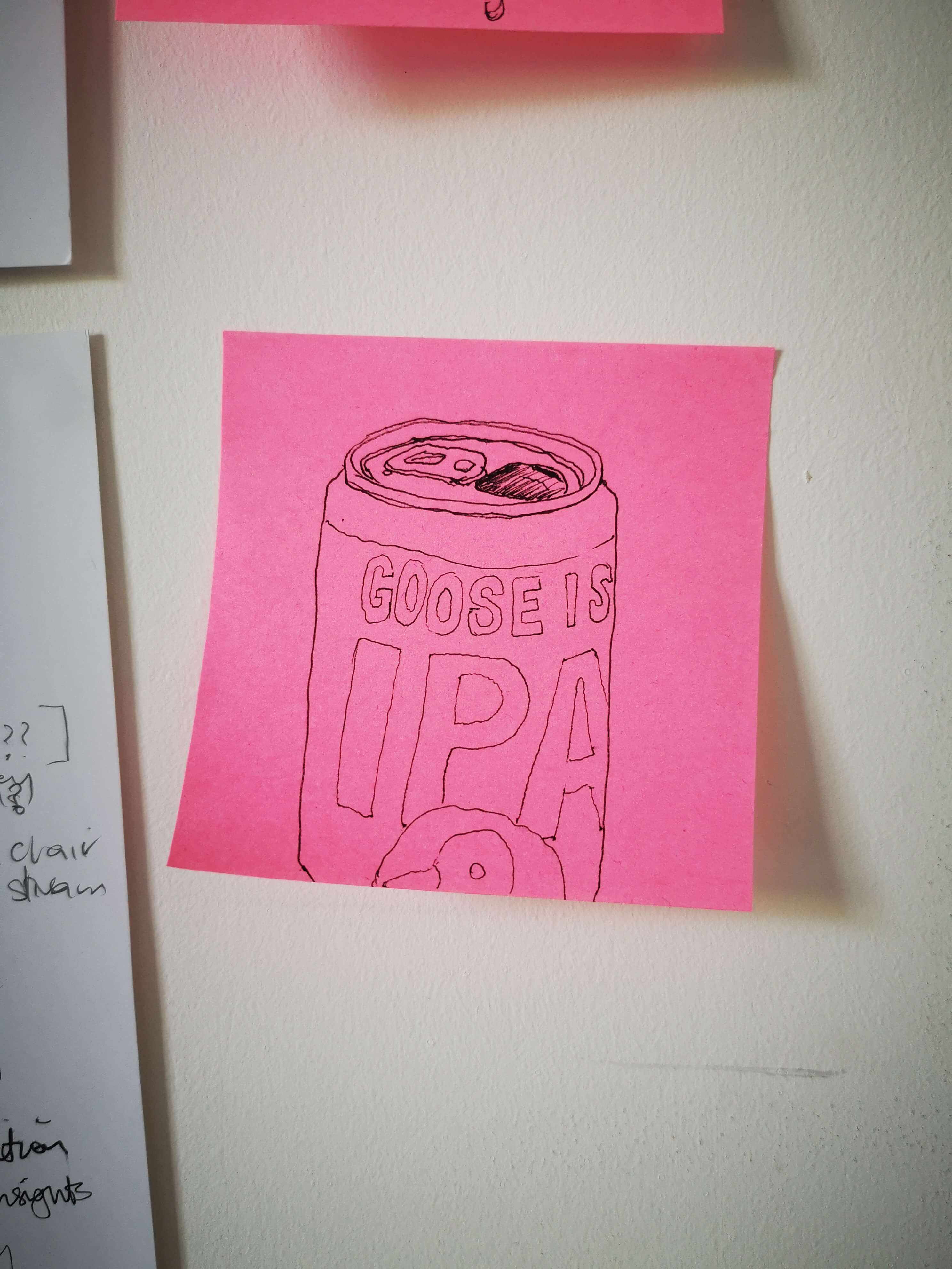 Photo of a flurescent pink Post-it note with sketch stuck to the wall. Sketch is of the Goose IPA can that I drank 